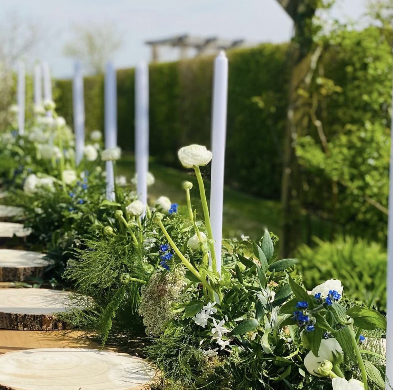 Wedding place settings at an outdoor table with a row of candles