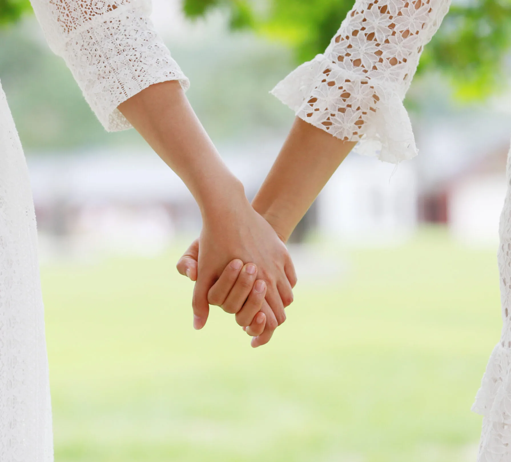 Two women in wedding dresses holding hands
